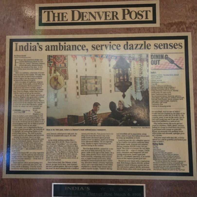 A framed newspaper clipping from The Denver Post about INDIA'S Restaurant, featuring a dining room photo.