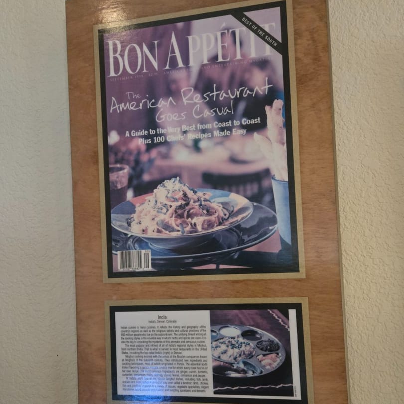 A framed Bon Appétit magazine cover featuring a pasta dish, and a framed description of Indian cuisine.