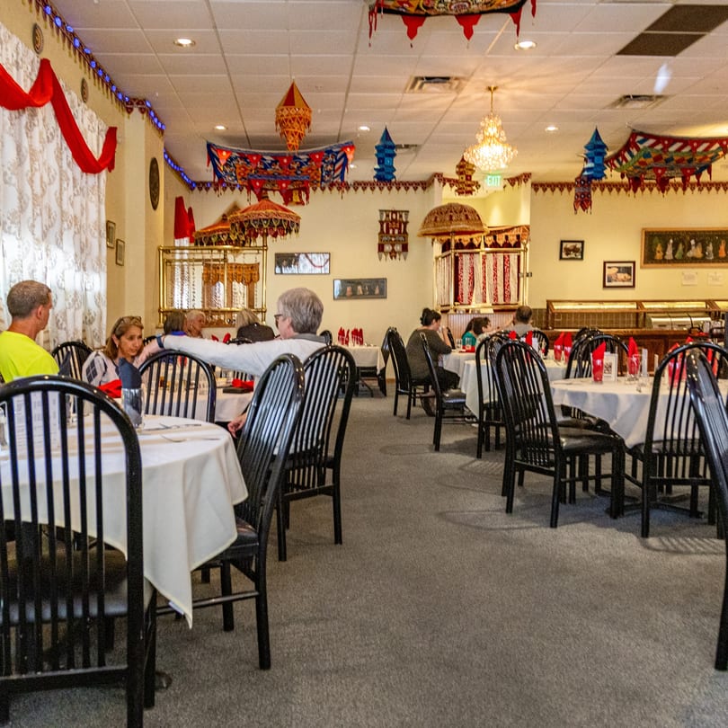 Diners seated at tables in INDIA'S Restaurant, featuring ornate Indian decor and a buffet line.
